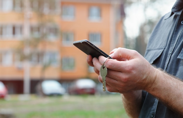 Foto hombre con el teléfono en el fondo de un edificio de varios pisos.