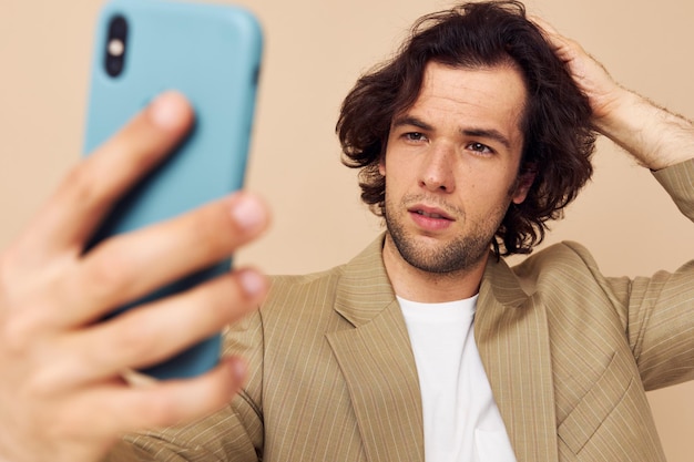 Hombre con un teléfono en la mano traje beige estilo elegante fondo aislado