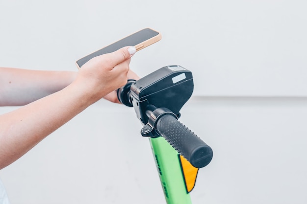 Un hombre con un teléfono en las manos usa una aplicación para un scooter eléctrico