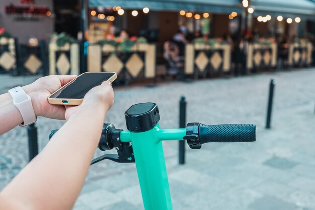 Un hombre con un teléfono en las manos usa una aplicación para un scooter eléctrico