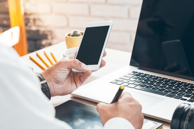 Hombre con teléfono móvil inteligente. Manos del hombre de negocios usando el teléfono celular en el escritorio de oficina.