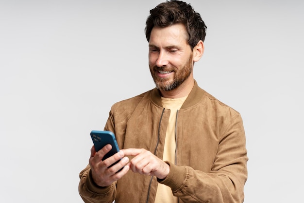 Foto hombre con teléfono móvil leyendo mensajes de texto comunicación en línea aislado en fondo gris