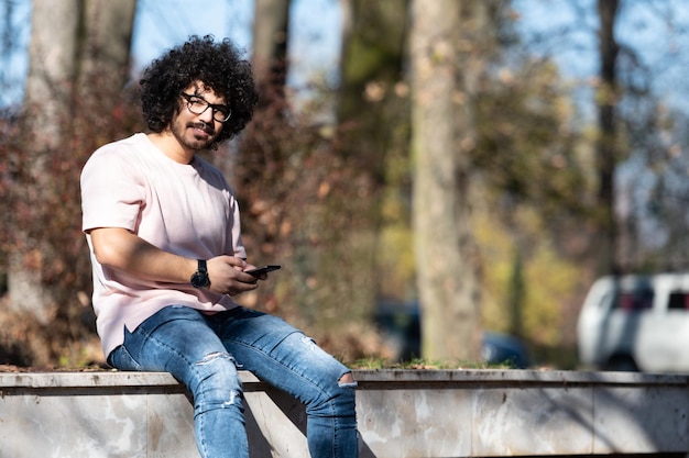 Hombre con teléfono móvil en el parque de otoño