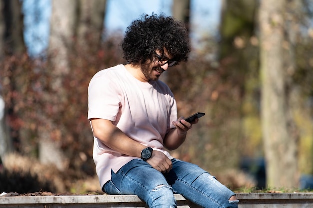 Hombre con teléfono móvil en el parque de otoño