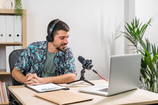 Hombre de telemarketer o podcast trabajando con un portátil y hablando por un auricular en la oficina del estudio