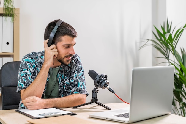 Hombre de telemarketer o podcast trabajando con un portátil y hablando por un auricular en la oficina del estudio