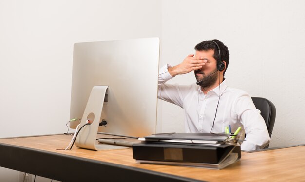 Hombre del telemarketer en una oficina que cubre ojos por las manos. No quiero ver algo