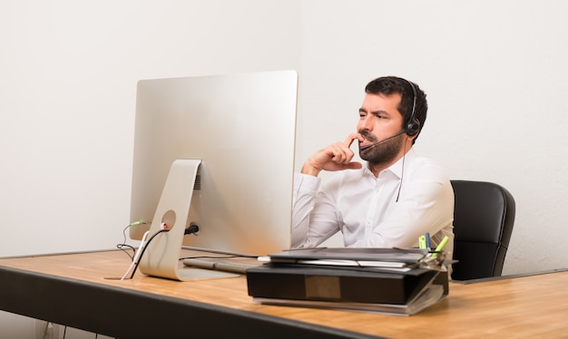 Hombre de telemarketer en una oficina que tiene dudas mientras mira hacia arriba