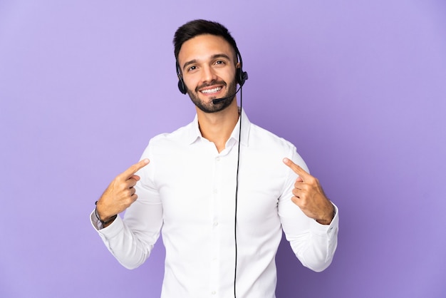 Hombre de telemarketer que trabaja con un auricular aislado sobre fondo púrpura dando un pulgar hacia arriba gesto