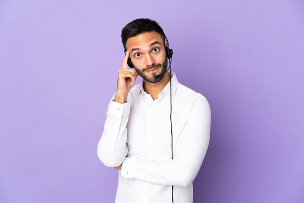 Hombre de telemarketer que trabaja con un auricular aislado sobre fondo púrpura pensando en una idea