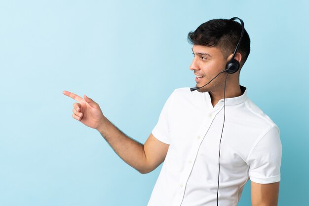 Hombre de telemarketing que trabaja con un auricular sobre el dedo acusador aislado hacia el lado y presenta un producto