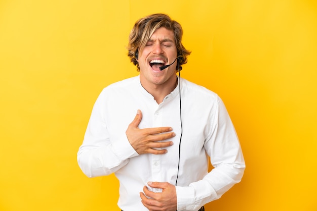 Hombre de telemercadeo que trabaja con un auricular aislado en amarillo sonriendo mucho