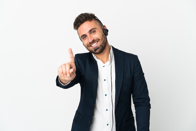 Hombre de telemercadeo que trabaja con un auricular aislado sobre fondo blanco mostrando y levantando un dedo