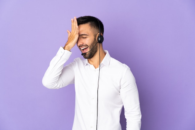 Hombre de telemercadeo que trabaja con un auricular aislado sobre fondo púrpura se ha dado cuenta de algo y tiene la intención de la solución
