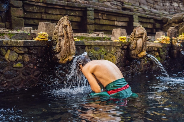 Hombre en el templo sagrado del agua de manantial en bali. El recinto del templo consta de un petirtaan o estructura de baño, famosa por su agua de manantial sagrada.