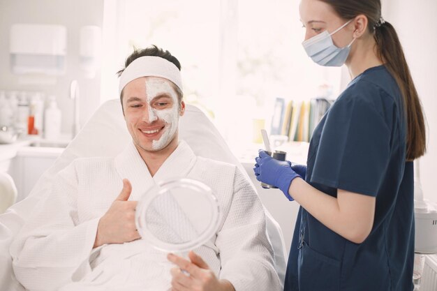 Hombre tendido en el gabinete de la cosmetóloga con una máscara aplicada en la cara