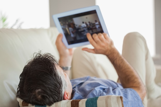 Hombre tendido en un sofá con una tablet pc