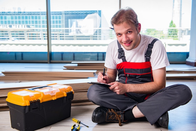 Hombre tendiendo pisos laminados en construcción