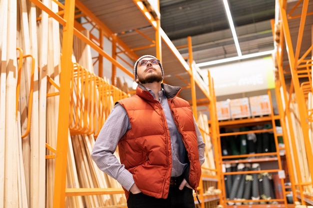 Un hombre en una tienda de madera examina el surtido mientras mira los estantes con productos