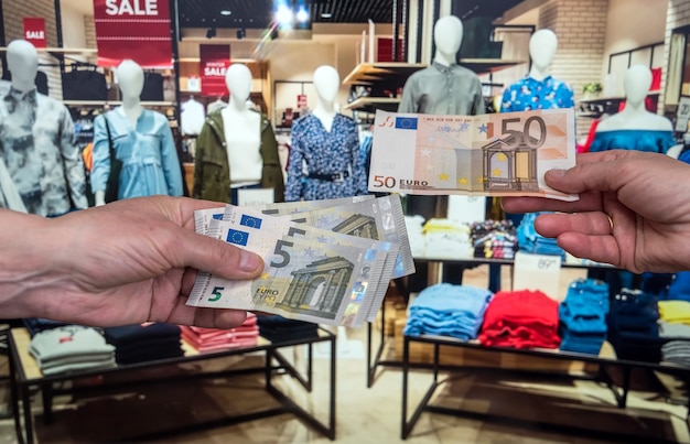 El hombre tiene billetes de euro en la tienda de ropa. concepto de compra