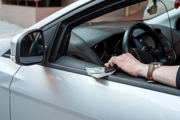 Foto el hombre tiene el dólar y la llave del coche para pagar el alquiler o la financiación de sobornos