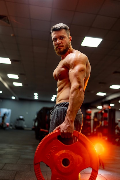 El hombre tiene entrenamiento en el gimnasio Tener ejercicio con panqueque amarillo para la varilla Enfoque selectivo