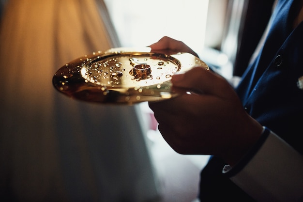 Hombre tiene placa de oro con anillos de boda en la iglesia