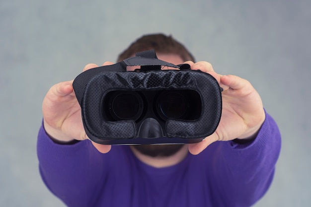 Foto el hombre tiene en sus manos gafas para realidad virtual y video de 360 grados. casco de realidad virtual para el teléfono inteligente sobre un fondo claro.