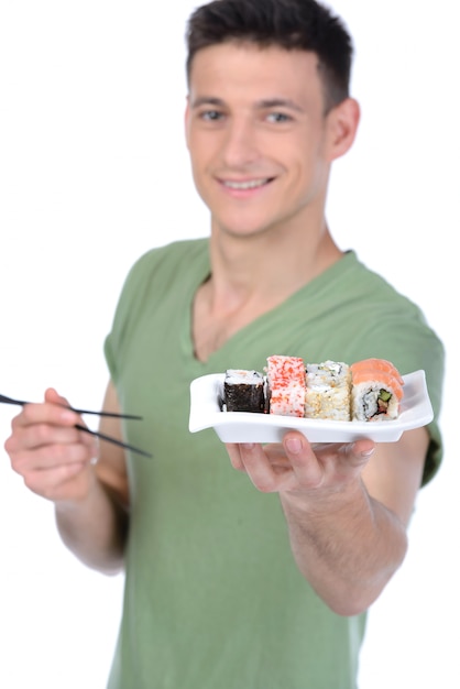 El hombre tiene sushi en la mano y sonríe.