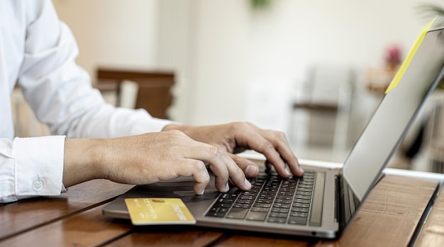 Un hombre tiene una tarjeta de crédito y usa una computadora portátil está llenando la información de la tarjeta de crédito