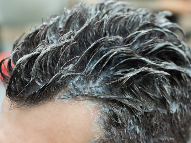 Un hombre se tiñe el pelo en el salón de belleza. Coloración del cabello de los hombres.