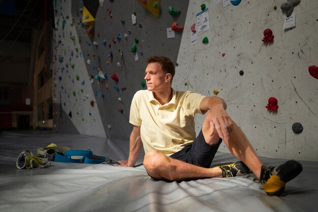 Foto hombre de tiro completo cerca de la pared de escalada