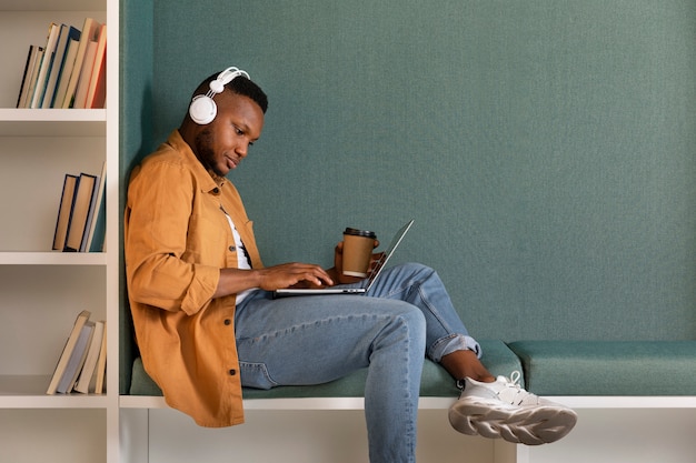 Hombre de tiro completo estudiando con auriculares