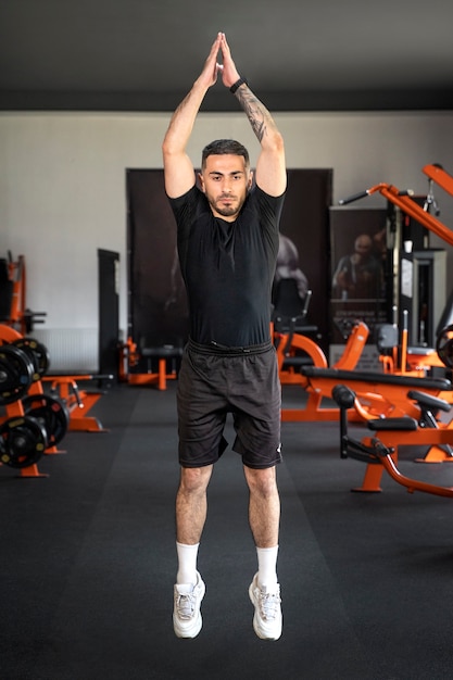 Hombre de tiro completo haciendo burpees en el gimnasio