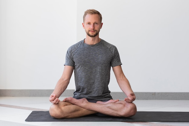 Hombre de tiro completo haciendo yoga dentro