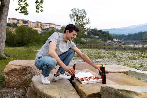 Hombre de tiro completo con pizza y bebidas.