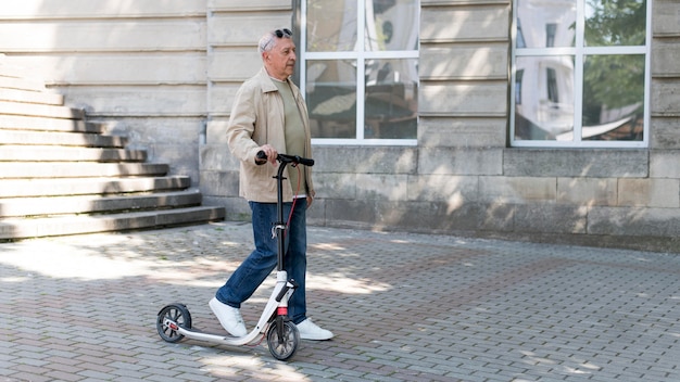 Foto hombre de tiro completo con scooter al aire libre