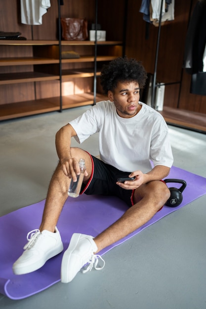 Foto hombre de tiro completo sentado en la estera de yoga