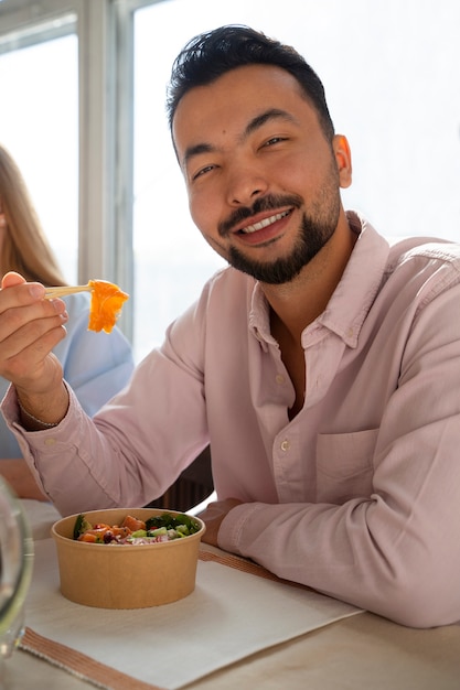 Hombre de tiro medio comiendo tazón de salmón