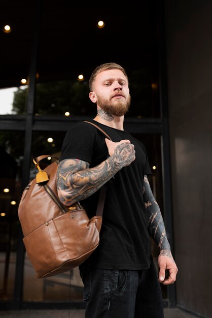 Hombre de tiro medio con tatuajes y mochila