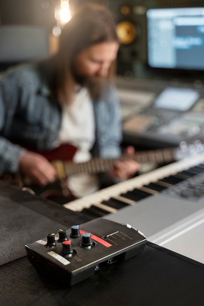 Foto hombre de tiro medio tocando la guitarra en el estudio