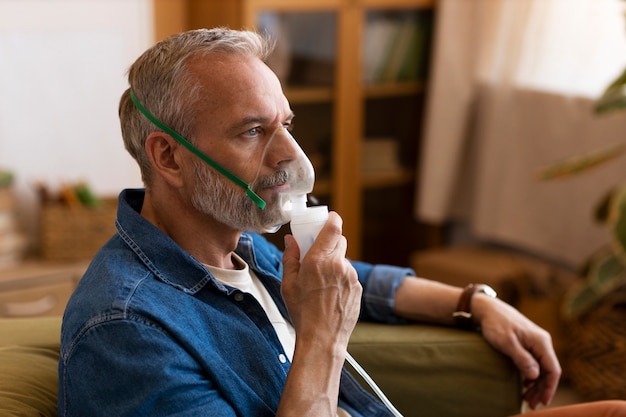 Foto hombre de tiro medio usando nebulizador