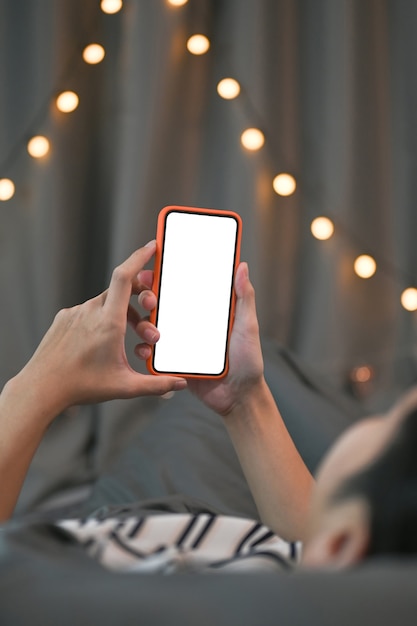 Hombre de tiro recortada acostado en la cama y usando teléfonos inteligentes.