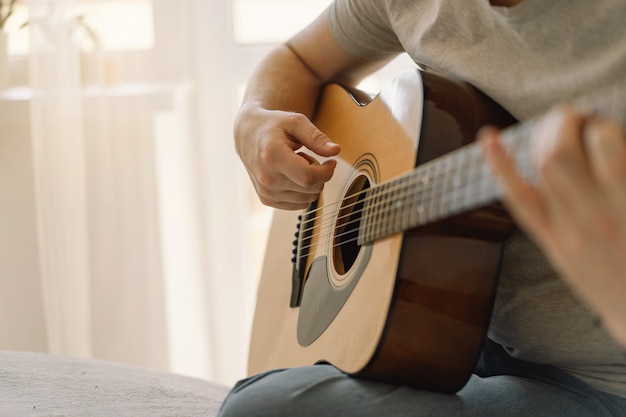 El hombre toca una guitarra acústica en una habitación en casa