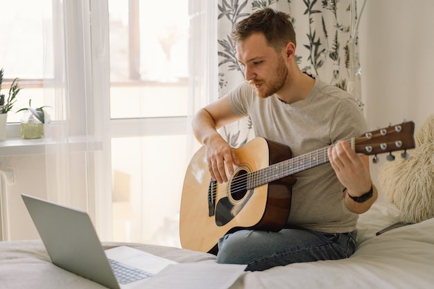 El hombre toca una guitarra acústica en una lección en línea