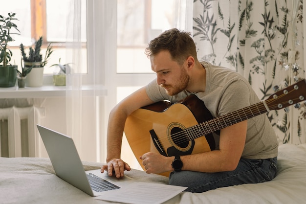 El hombre toca una guitarra acústica en una lección en línea