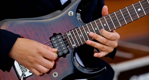 Un hombre toca una guitarra electrónica moderna. Manos en cuerdas. . Foto de alta calidad