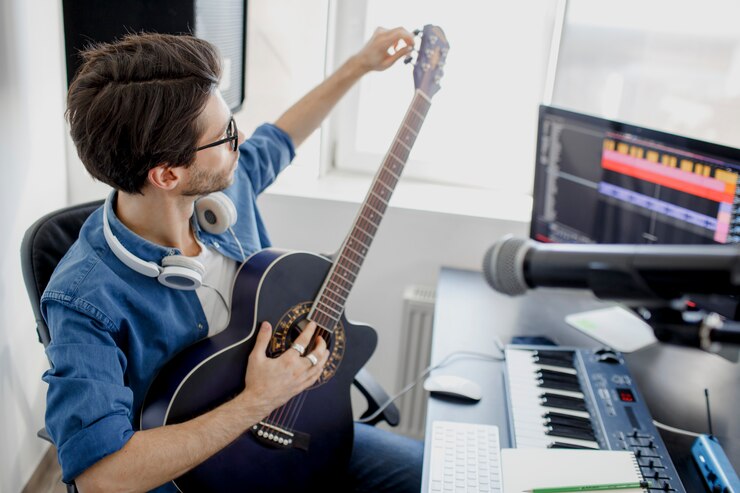 Foto el hombre toca la guitarra y produce una banda sonora electrónica o una pista en un proyecto en casa. arreglador de música masculina componiendo canciones en piano midi y equipo de audio en estudio de grabación digital.