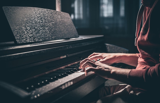 Un hombre toca un piano electrónico en un cuarto oscuro.