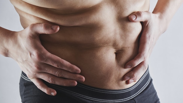 El hombre toca su vientre gordo closeup, obesidad, pérdida de peso masculina y concepto de dieta